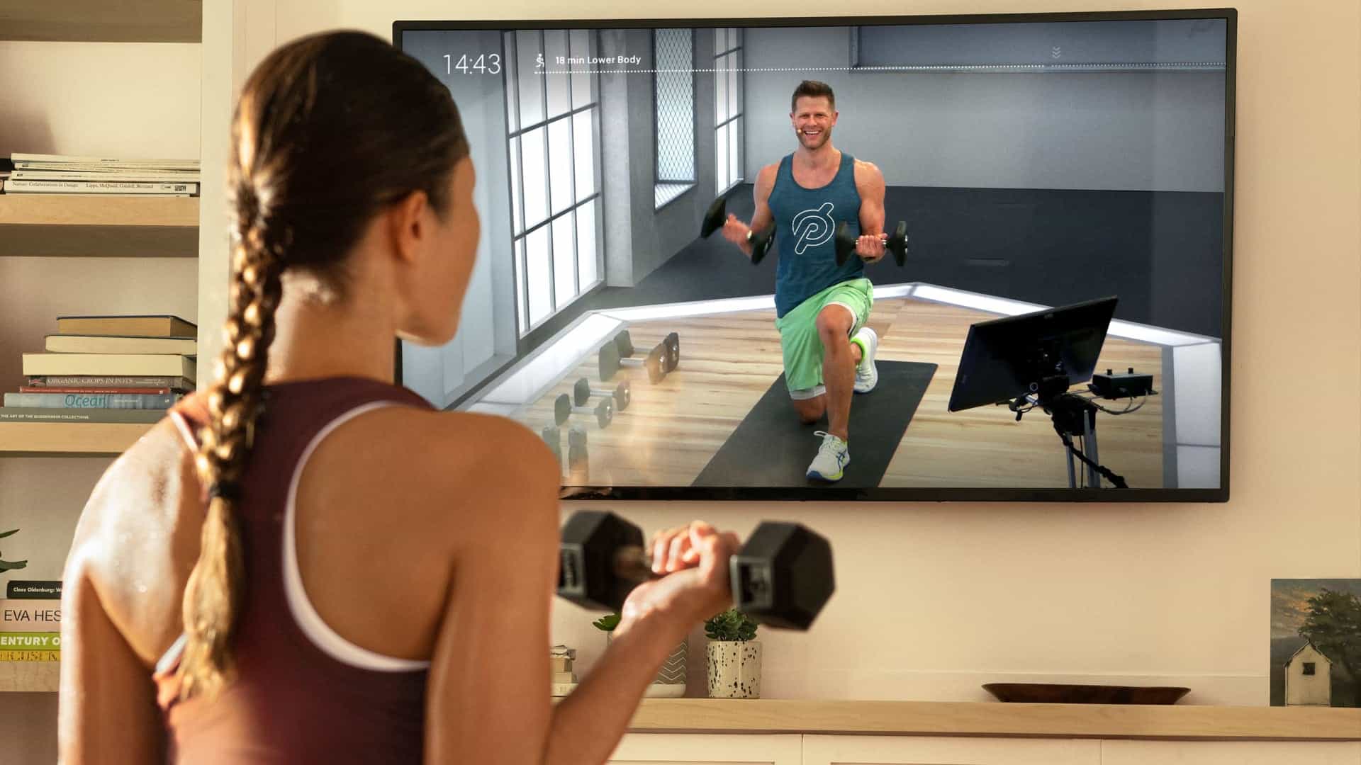 Woman working out with dumbells using the Peloton app on TV