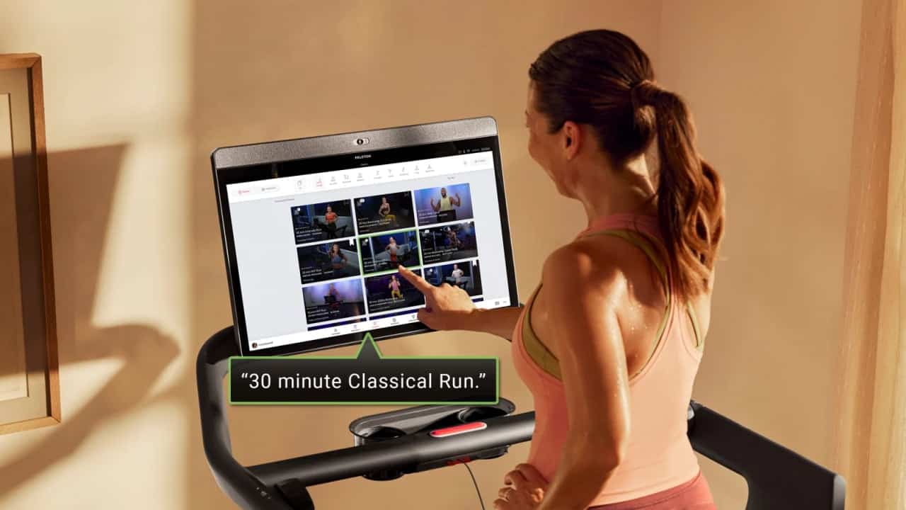Woman touching touchscreen while exercising on Peloton Treadmill